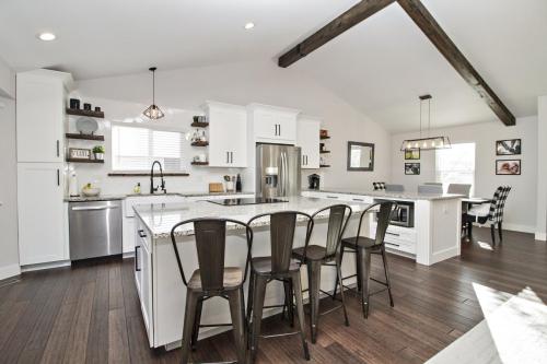 Copy-of-Open-Concept-Kitchen-Dining-White-Tile-Backsplash-Light-Grout-Wood-Beams-Granite-Countertop-White-Cabinets-Farmhouse-Stainless-Steel-Appliances-Floating-Wood-Shelves-Dark-Hardwood-Floor-Pendant-Light-War-Eagle